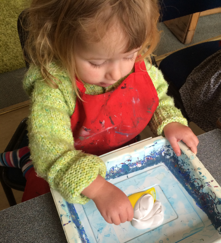 A young child mixes paint. Learning science concepts takes time.