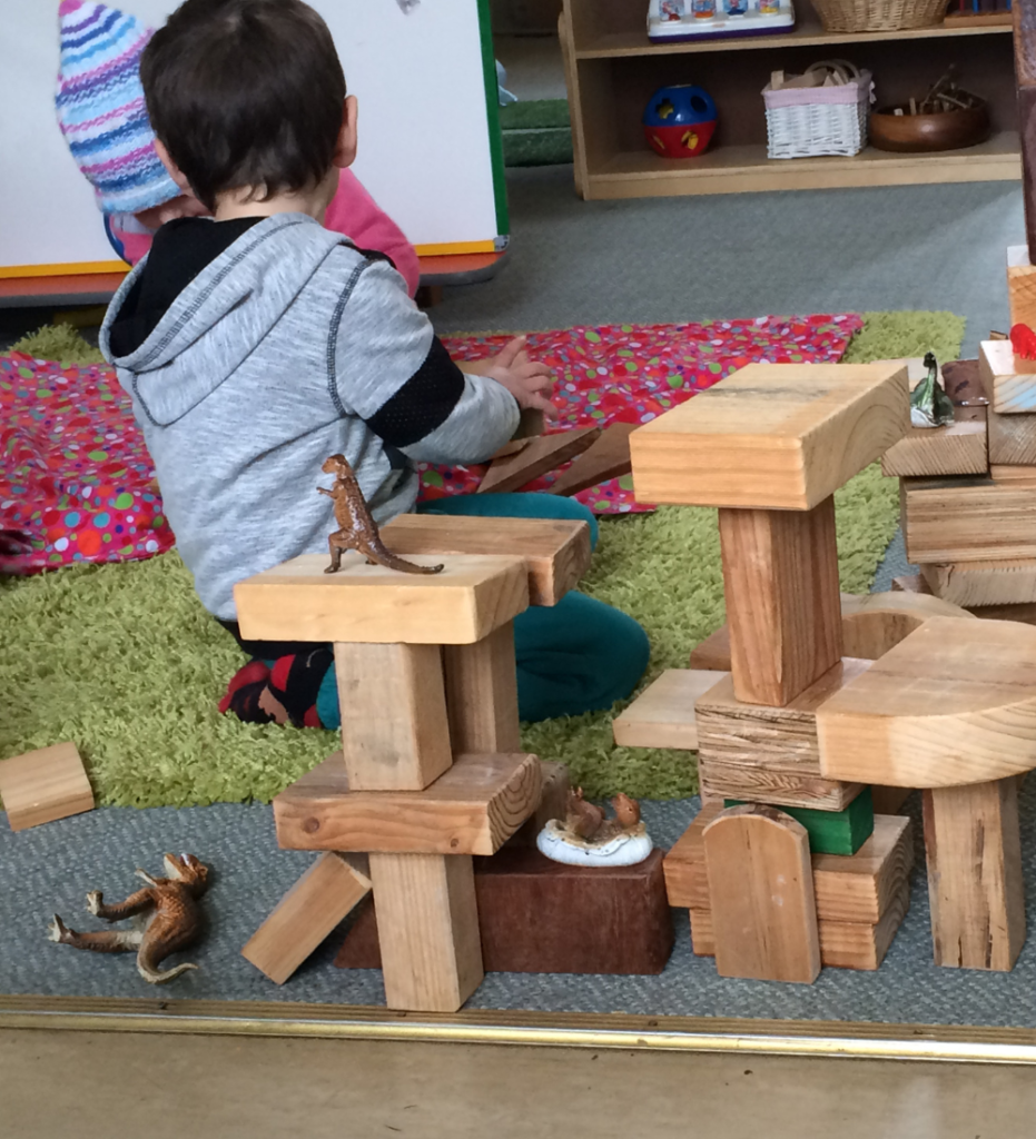 A young child stack up wooden blocks to create towers. The best materials for science learning have no 'right' or 'wrong' answers.