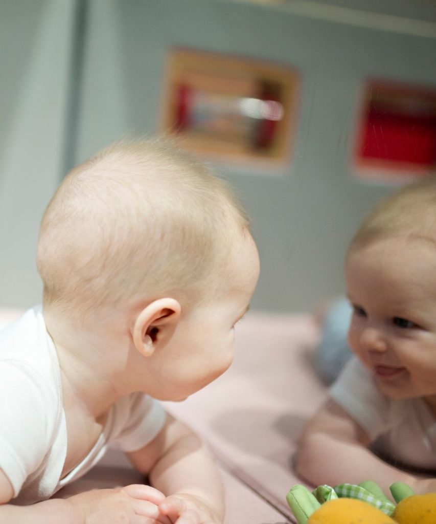 Baby looks at reflection in mirror. This is everyday science.